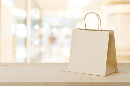 Brown paper shopping bag on wood table over blurred store background, business, template, retail, saleの写真素材