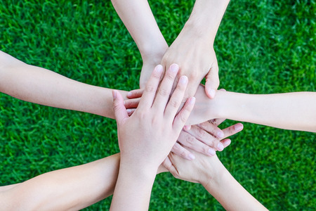 Business team hands joining together over green yard background, business teamwork, cooperation...