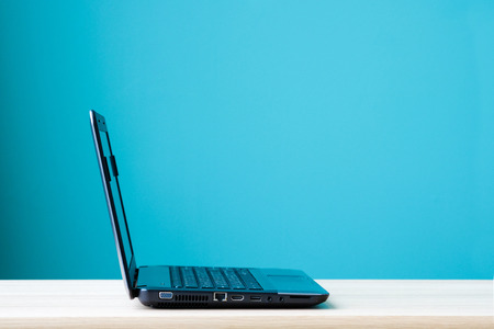 Computer notebook, lap-top, on office desk over green wall background, with copy spaceの写真素材