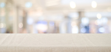 Empty table with linen tablecloth over blurred store with bokeh background banner, product display montageの写真素材