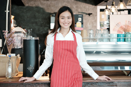 Young asian women Barista standing with smiling face in font of cafe counter background, small business owner, food and drink industry conceptの写真素材