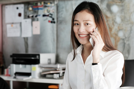 Young businesswoman talking smart phone at office background, business communication conceptの写真素材