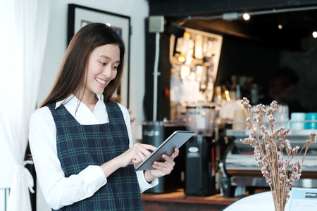 Young asian woman using tablet at cafe background, food and drink conceptの写真素材