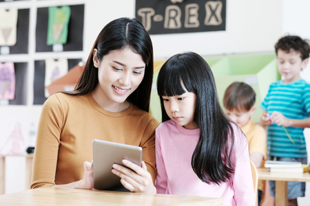 Young teacher teching kid by using tablet, education online, technology lifestyleの写真素材