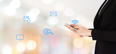 Businesswoman hands using smart phone and the internet of things icon over blur office with bokeh light background, banner, business on phoneの写真素材