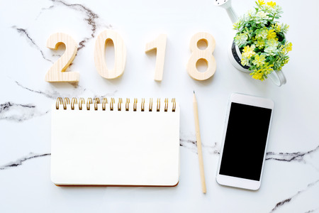 2018 wood letters, blank notebook paper, white smart phone with blank screen and pencil on white marble table background, 2018 new year mock up, template with copy space for text, top viewの写真素材