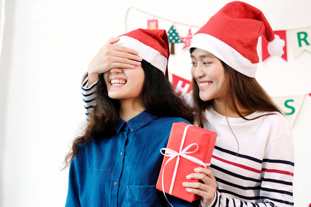 Two young asia women giving surprise Christmas gift, Christmas celebration relationship couple, LGBT and friends conceptの写真素材