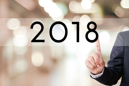 2018 business banner, Businessman hand touch 2018 button over blur office background, new year business conceptの写真素材