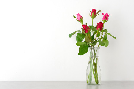 Red and pink roses in glass vase on table and white wall background with copy space, Happy valentine's day conceptの写真素材