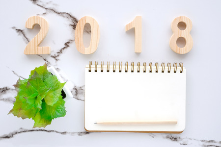 2018 wood letters, blank notebook paper and pencil on white marble table background, 2018 new year...