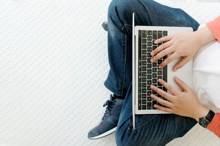 Man using laptop computer while sitting on white floor background with copy space, top view, people...