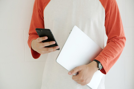 Man holding laptop computer and using smart phone, people and technology, lifestylesの写真素材