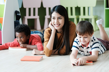 Young asian woman teacher and American, African boys in kindergarten classroom, preschool education conceptの写真素材
