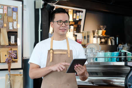 Young asian barista taking note, order, at coffee cafe counter with smiling face, food and drink business conceptの写真素材