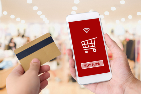 Hand holding credit card and smart phone with shopping online icon on device screen background, shopping online, business, finance and technology, online payment, digital money conceptの写真素材