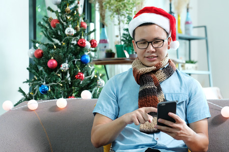 Young asian man using smart phone at Christmas party, Christmas people celebration conceptの写真素材