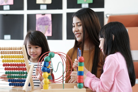 Young asian woman teacher teaching girl in kindergarten classroom, preschool education conceptの写真素材