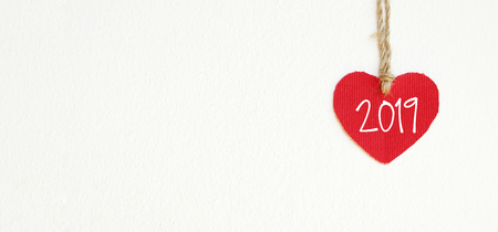 2019 new year greeting card template, Red fabric heart with 2019 word hanging on white wall background with copy spaceの写真素材
