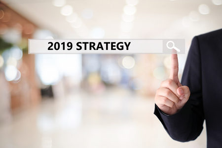 Businesswoman hand touching 2019 strategy on search bar over blur office background, success in business conceptの写真素材