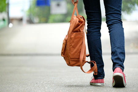 Back of student girl holding school bag while walking in school campus background, education, back to school conceptの写真素材