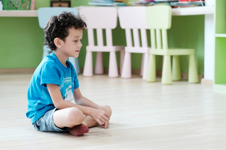 White boy sitting in kindergarten classroom with happy emotional, preschool education concept
