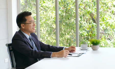 Senior asian businessman working on document at his office desk, business people, office lifestyle conceptの写真素材