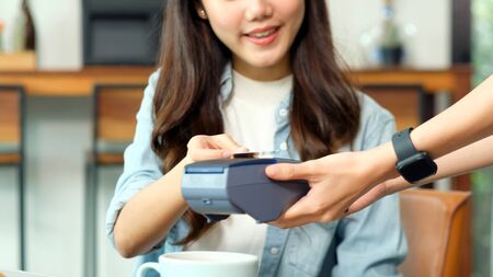 Young asian woman holding credit card for paying contactless at coffee shop, cafe background, Small business financial and contactless payment concept, close upの写真素材