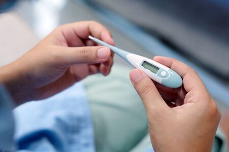 Closeup of man looking at thermometer, Male hand holding a digital thermometer when measures the...