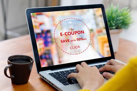 E-coupon, Grocery shopping online, Woman hand using laptop computer with discount coupon on screen, online shopping sale, digital marketing, retail business and technology, e commerce promotion conceptの写真素材