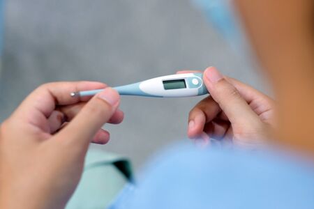 Closeup of man looking at thermometer, Male hand holding a digital thermometer when measures the...