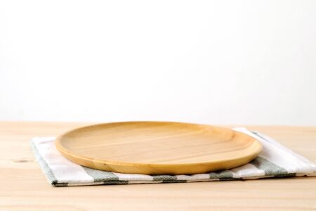 Empty round wooden plate on wood table and cement wall background, food display montageの写真素材