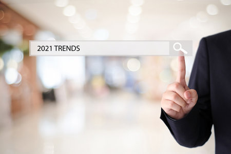 Man hand touching 2021 trends on search bar over blur office background, success in business...