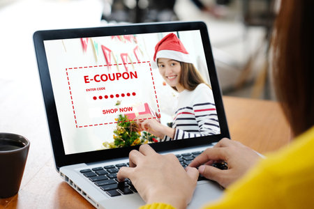 Woman entering Christmas discount coupon code on laptop screen to get the shopping online promotion, online shopping ,digital marketing business and technologyの写真素材