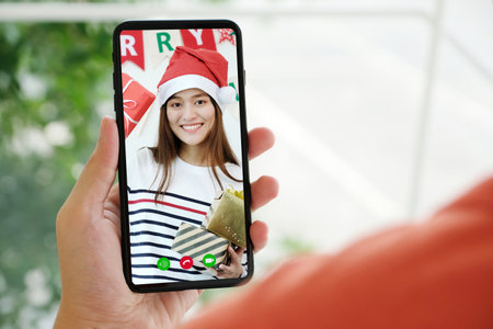 Asian girl video call for greeting in Christmas celebration, Hand holding mobile phone while talking...