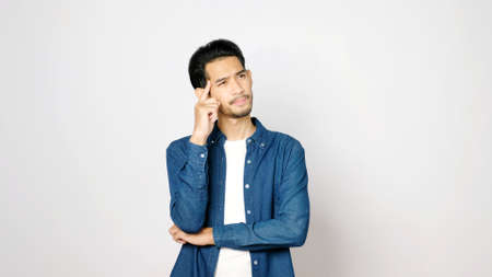 Young asian man doubting while standing over isolated gray background, Portrait of confused handsome...