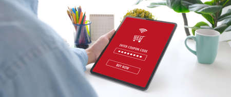 Hand holding discount coupon code on digital tablet screen to get the shopping online promotion, on line shopping ,digital marketing business and technology, lifestyle conceptの写真素材
