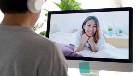 Young asian woman greeting her friend by virtal video conference at home, social distancing, telecommunicationの写真素材