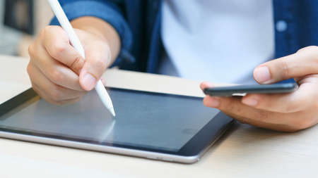 Close up of man hand writing on digital tablet while working at home, online study,...