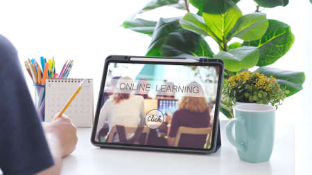 Online studying class, Student man hand writing on notebook while using digital tablet for e learning, Adult male university, college student study online course at home, educationの写真素材