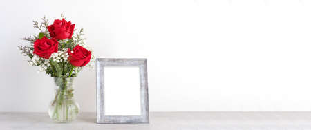 Valentineâs day concept, Red roses flower bouquet in glass vase and blank grey vintage wooden frame on table background with copy space , Banner for mock up, templateの写真素材
