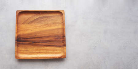 Empty wooden plate on gray cement table background, banner with copy space, Blank wood tray for food display montage, template, mock up, top view, flat layの写真素材