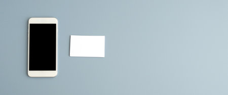 Mobile phone with blank screen and blank business card on gray background with copy space, banner, template, mock upの写真素材