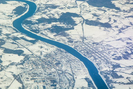 The surface of the Earth from the airplane window. The fields are covered with snow. Black forest....