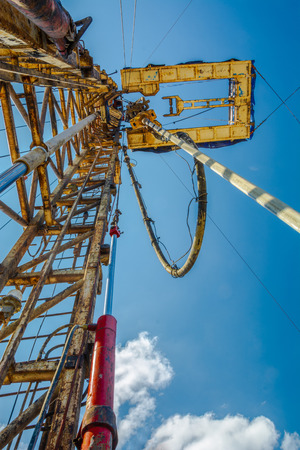 Drilling a well for oil and gas production at the field. Derrick, equipment and tools for drilling wells. The pipe rotates and goes into the well.の写真素材