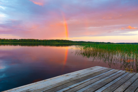 Summer evening by the lake. Landscape with sunset and a rainbow on the horizon.の写真素材
