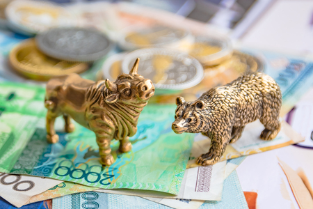 Bronze figures of a bull and a bear on the background of paper money and metal coins. Blur background and perspective. Concept and symbol of stock exchange and stock trading.の写真素材