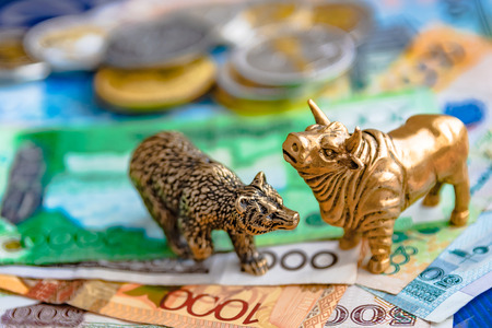 Bronze figures of a bull and a bear on the background of paper money and metal coins. Blur background and perspective. Concept and symbol of stock exchange and stock trading.の写真素材