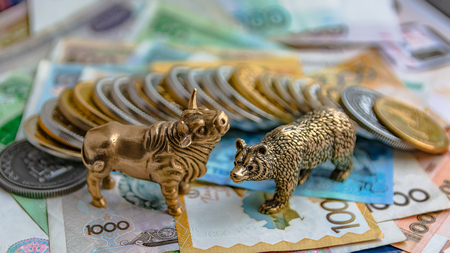 The bronze bull and bear figurines are arranged with paper money and metal coins. Blur background. Symbol and concept of trading on the stock exchange.の写真素材