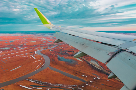 Colorful top view of the spring northern tundra and lakes from the airplane porthole. Also visible is the wing of the flying plane.の写真素材