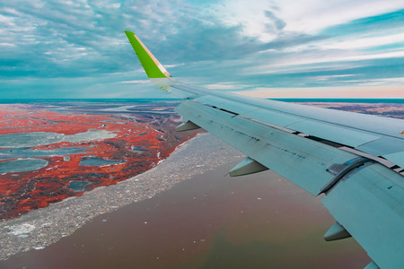 Colorful top view of the spring northern tundra and lakes from the airplane porthole. Also visible is the wing of the flying plane.の写真素材